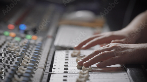 close up shot of the musician's hands, the professional records the music in the sound recording studio, the man moves the sliders on the mixer