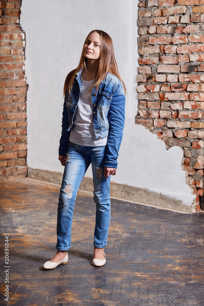 Hipster girl wearing white cotton t-shirt, denim jacket,jeans posing  against rough brick wall, minimalist urban clothing style. Full-length  young woman teenager model in stylish casual clothes. Stock Photo | Adobe  Stock