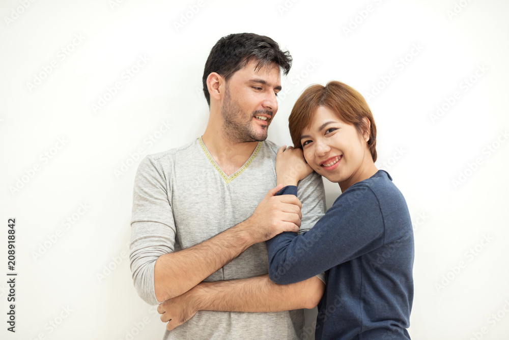 Couple hugging while standing over white wall. Couple hugging while standing over white wall.