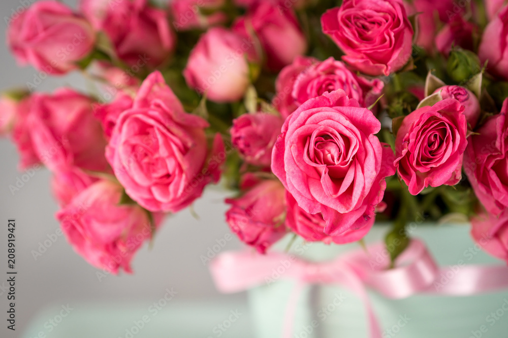 bouquet of pink roses in a mint-colored pot on a blurred background