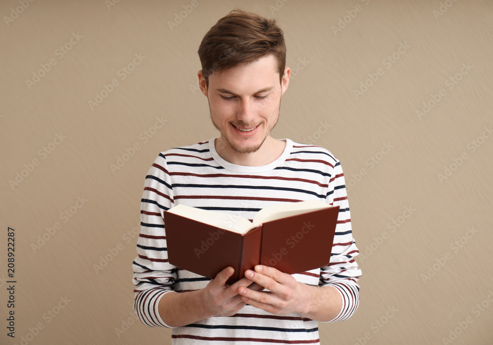 Young man reading book on color background Young man reading book on color background