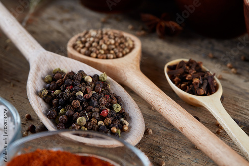 Various spices in wooden spoons and bowls and some salt on an old wooden barrel, top view, close-up, selective focus.