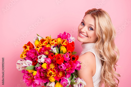 Portrait of pretty charming gorgeous girlfriend, elegant wife, positive mother having big bouquet of colorful aromatic tulips looking at camera isolated on pink background
