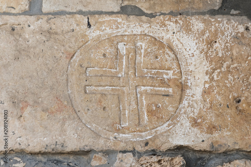 A cross carved on a stone wall on the facade of a church of the Christian Maronites in the abandoned village Kafr Birim in the north of Israel photo