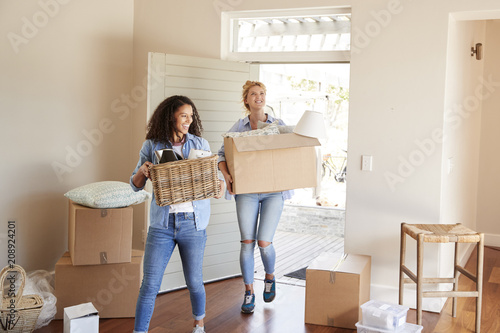 Female Friends Carrying Boxes Into New Home On Moving Day