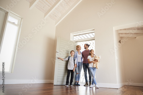 Family Opening Door And Walking In Empty Lounge Of New Home