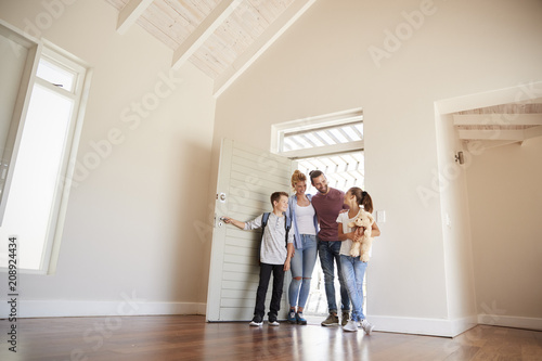 Family Opening Door And Walking In Empty Lounge Of New Home