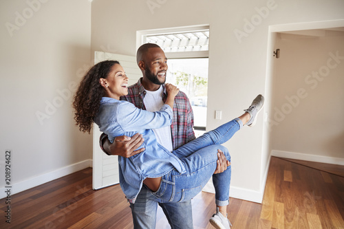Man Carrying Woman Over Threshold Of Doorway In New Home photo