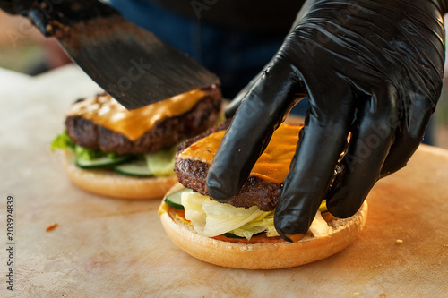 Chef making beef burger with cheese on open kitchen. Street fast food. photo