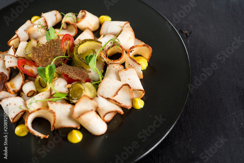 dish of many pieces of lard with vegetables on black background