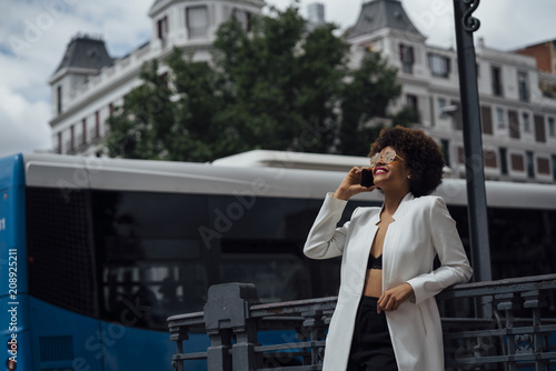 Beautiful Afro hair girl with mobile phone in the streets of Madrid Spain