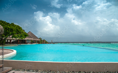Maldives infinity pool beautiful beach background white sandy tropical paradise island with blue sky sea water ocean  © Maria