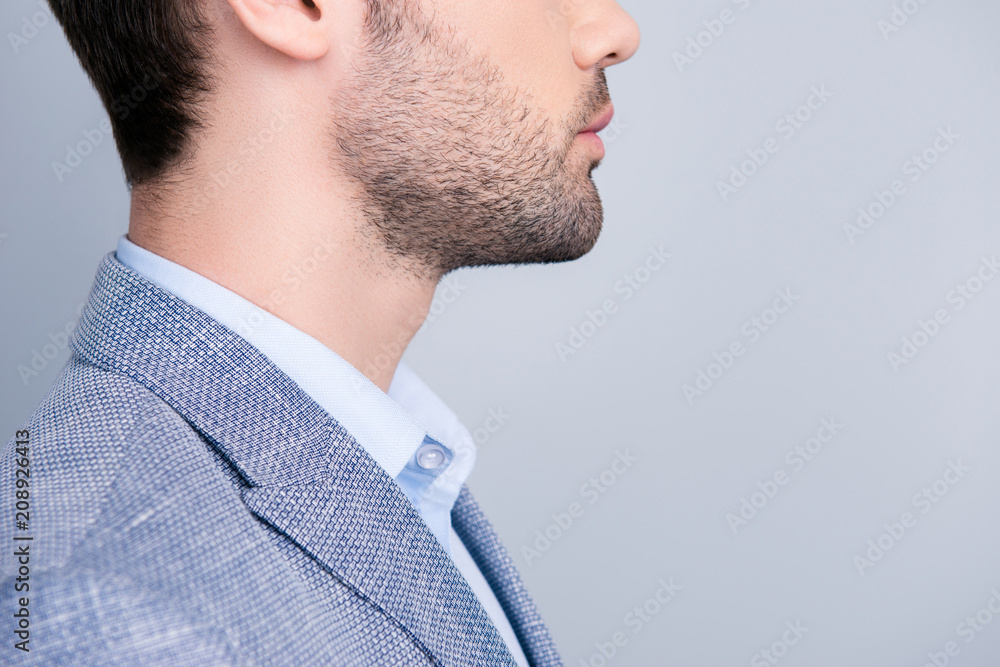 Fototapeta premium Side view cropped half face profile portrait with copy space of stunning manly manager in suit with serious expression isolated on grey background