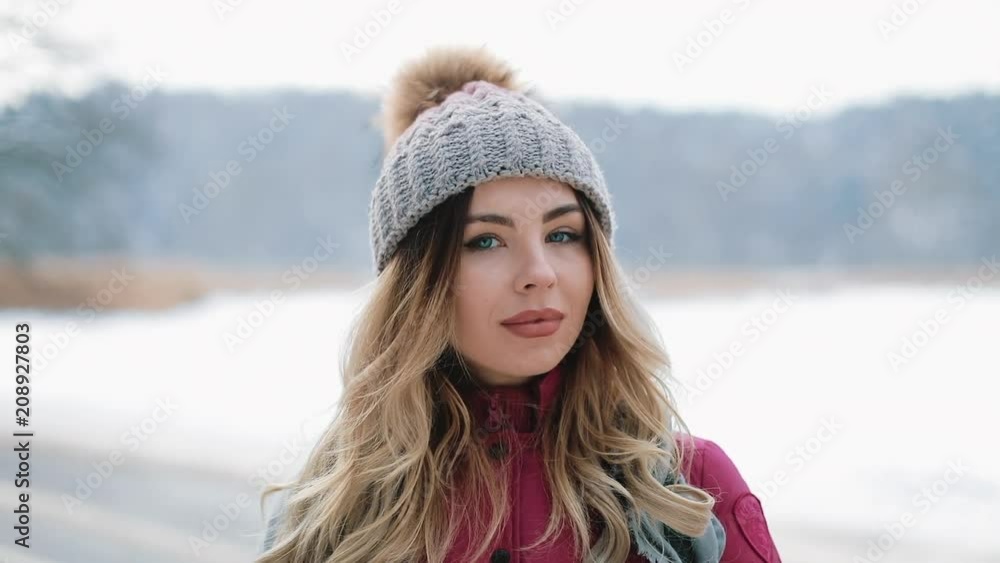 Pretty woman in winter hat smiles standing outside on the snow Pretty woman in winter hat smiles standing outside on the snow