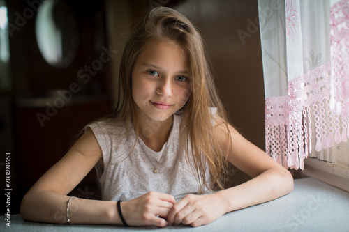 Canvas Print Portrait of cute little girl sitting at the table.