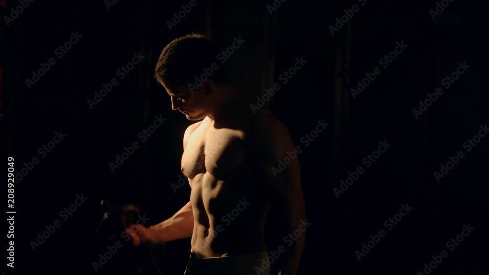 Fototapeta premium Mman with well trained body, biceps, abs and pecs make exercise with dumbbell