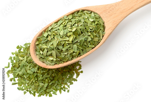 dried tarragon leaves in the wooden spoon, isolated on white, top view