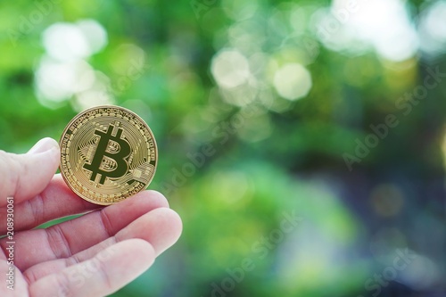 Bitcoin in hand with green blur background, bitcoin concept, copy space