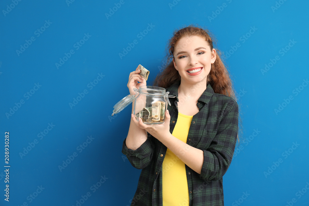 Young woman putting dollar banknote into glass jar with money on color background. Money savings concept Young woman putting dollar banknote into glass jar with money on color background. Money savings concept