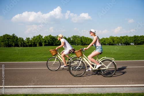 Portrait of sportive beautiful brother and sister riding on retro bikes outdoor over nice landscape enjoying weekend together. Meadow forest daydream recreation refreshment concept