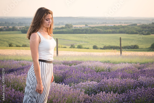 Fototapeta Naklejka Na Ścianę i Meble -  Beautiful young woman is walking on the lavender field