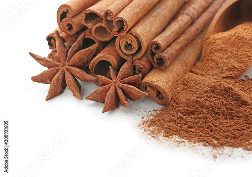Cinnamon sticks with powder and anise stars on white background, closeup