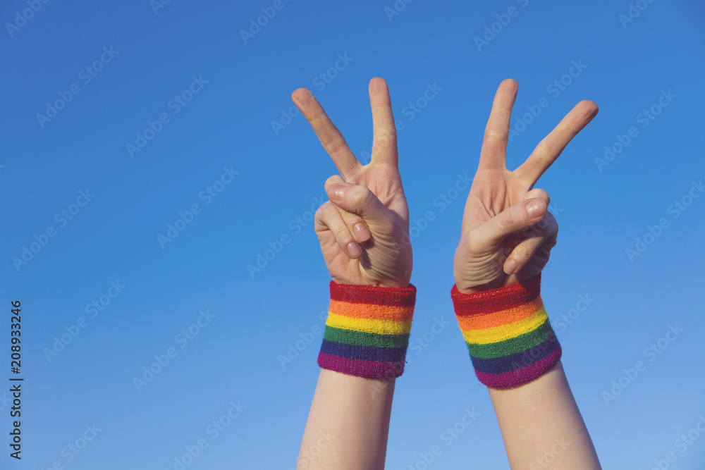 Gay pride concept. Hand making a V peace sign with gay pride LGBT rainbow flag wristband Gay pride concept. Hand making a V peace sign with gay pride LGBT rainbow flag wristband