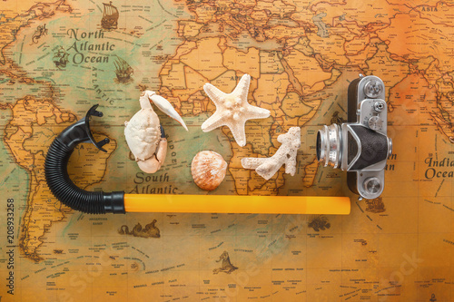Sea shells, an old camera and a snorkel tube lie on a vintage map. Copy space.