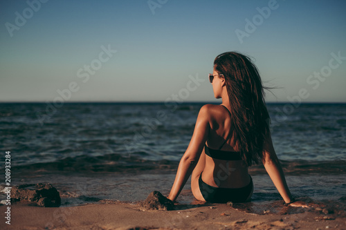 Girl sitting on the beach and looking to the side