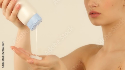 woman pouring body cream on her face