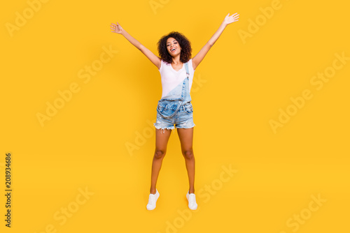 Full size portrait of funny crazy girl jumping in air holding hands up making star pose looking at camera isolated on yellow background. Luck success achievement concept