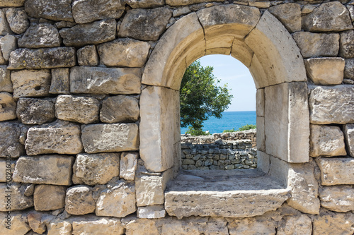 wall with a window in the ruins of an ancient city overlooking the sea  selective focus