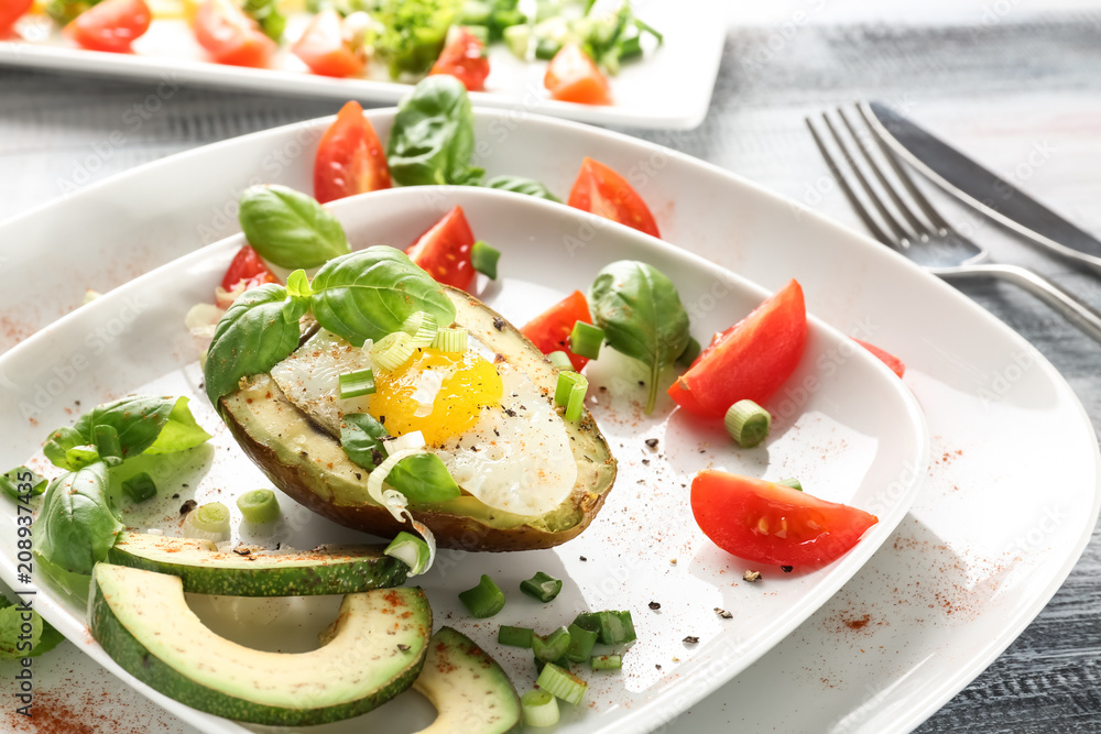 Tasty baked avocado with egg and fresh vegetables on plate, closeup Tasty baked avocado with egg and fresh vegetables on plate, closeup