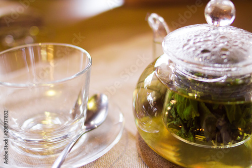 Beverages, good morning and breakfast concept - empty tea cup and teapot with green tea on the table