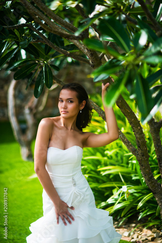 Bride posing in wedding dress with tropical tree