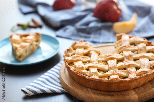 Wooden board with tasty homemade apple pie on table