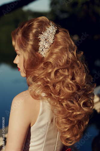 Closeup of hairstyle with barrette or bobby pin in girls hair. Golden hair woman at sunset in park.