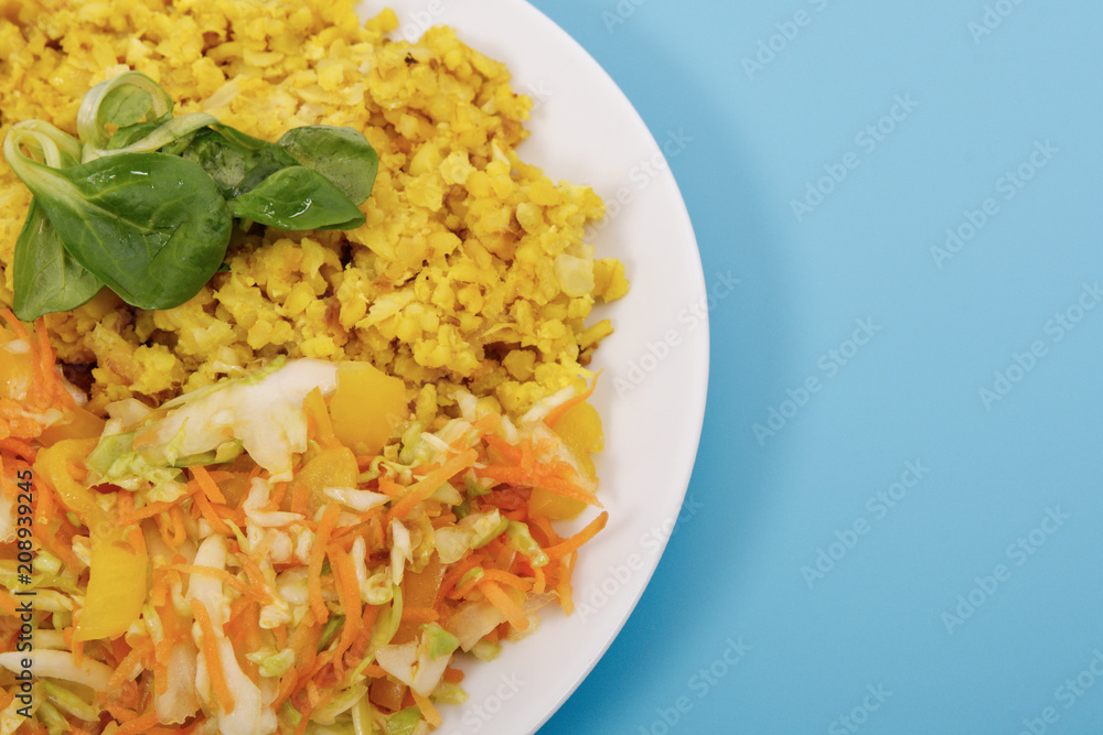Baked Bulgar with cauliflower and vegetable salad on a blue Baked Bulgar with cauliflower and vegetable salad on a blue