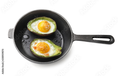 Baked avocado with eggs in frying pan on white background