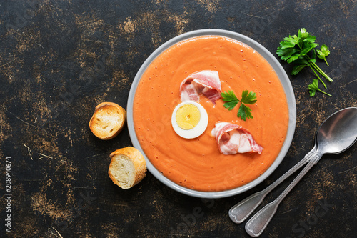 Traditional spanish andalusian tomato cream soup salmorejo served in a gray plate with ham and egg. photo