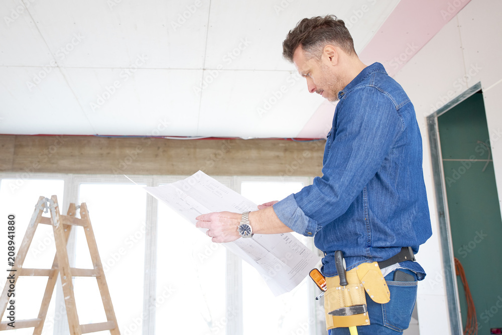 Construction man holding blueprint in his hand and working