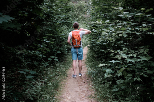 young attractive sporty man walking along a path in the forest