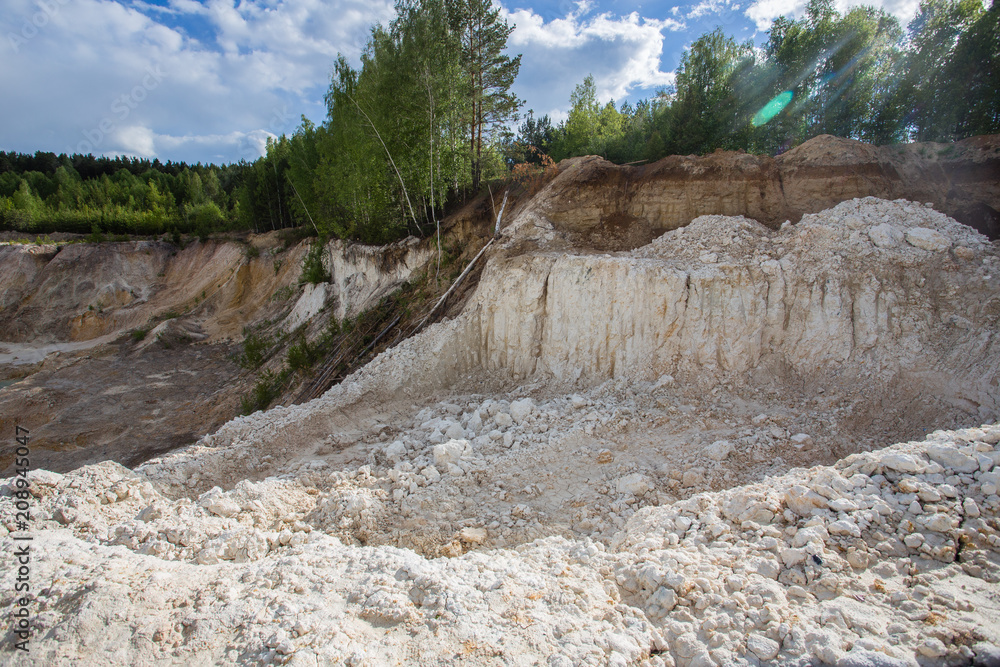 Open pit quarry ore white kaoline mining with blue sky and water