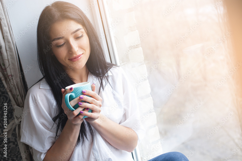 Young attractive woman drinking tea or coffee at her kitchen. Lady indors relaxing with cup of hot drink Young attractive woman drinking tea or coffee at her kitchen. Lady indors relaxing with cup of hot drink