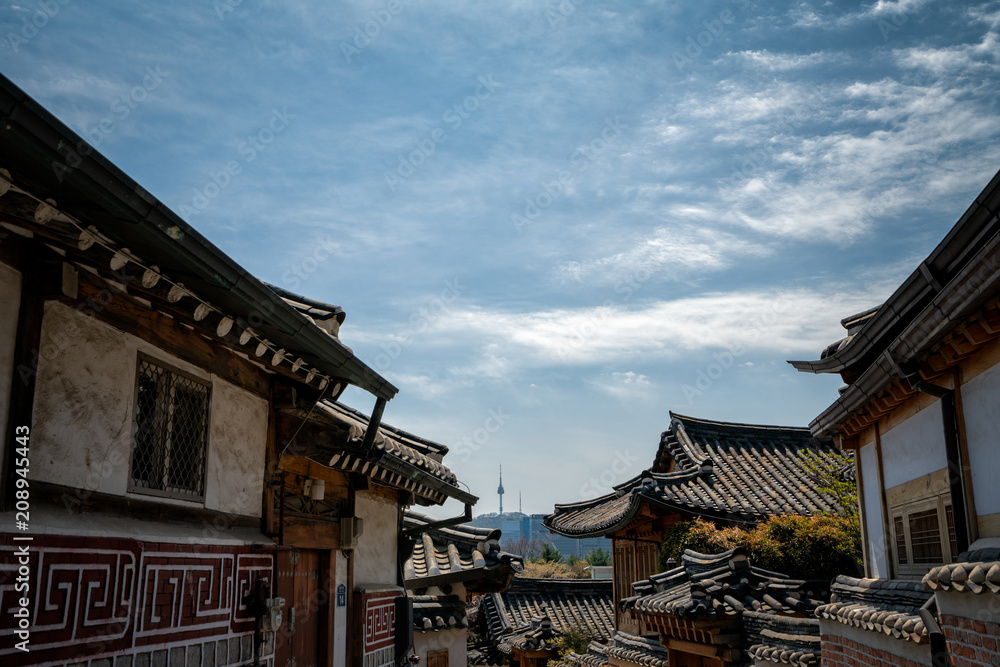 Traditional korean style architecture in Bukchon Hanok Village with N Seoul Tower on Namsan mountain in background at Seoul, South Korea.