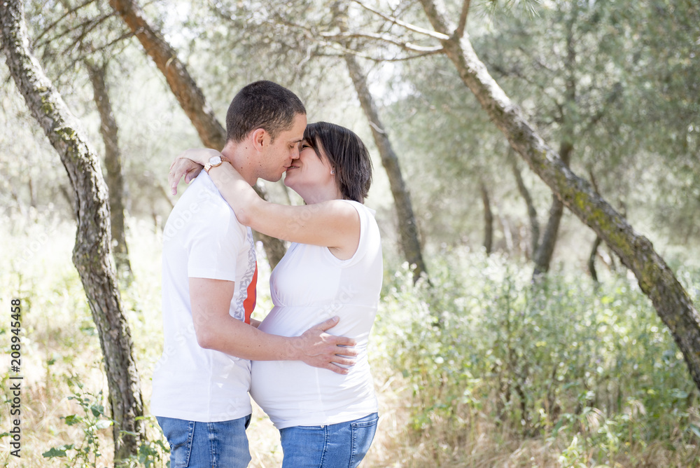 Pregnant and her Husband Posing in the Park Pregnant and her Husband Posing in the Park