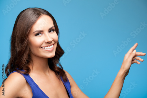 Woman showing copyspace or something, over blue
