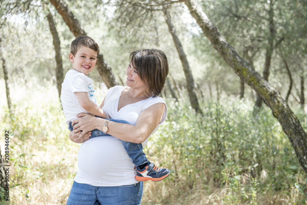 Fototapeta premium Pregnant woman and her son posing in the park