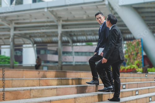 business man walking up staircase at outdoor in city talking and discussion about planning project progress to successful.