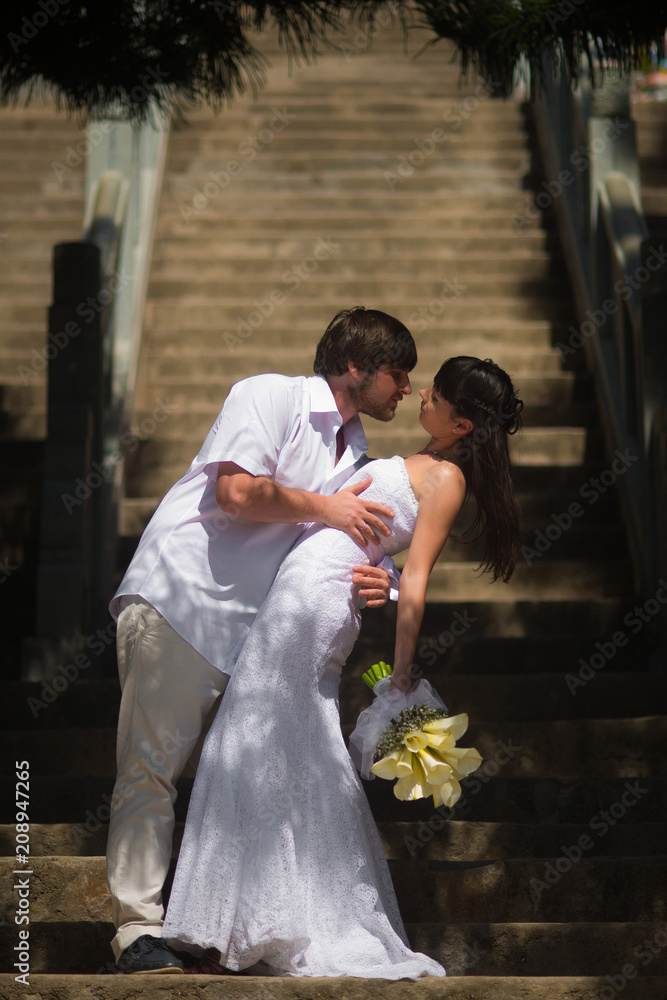 The bride and groom stand on the stone steps